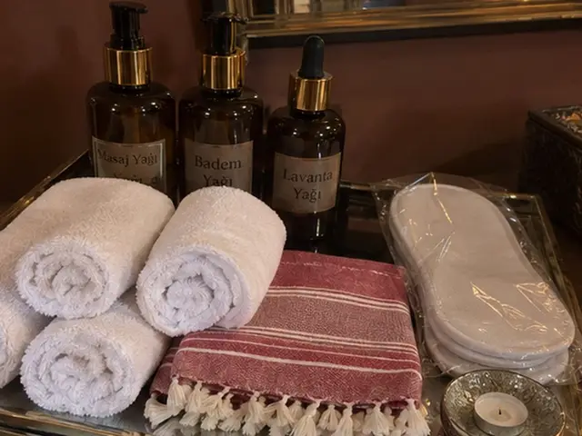 Masaj yağları, rulo havlular, kırmızı çizgili peştemal ve terlik — Haznedar, Masaj Salonun